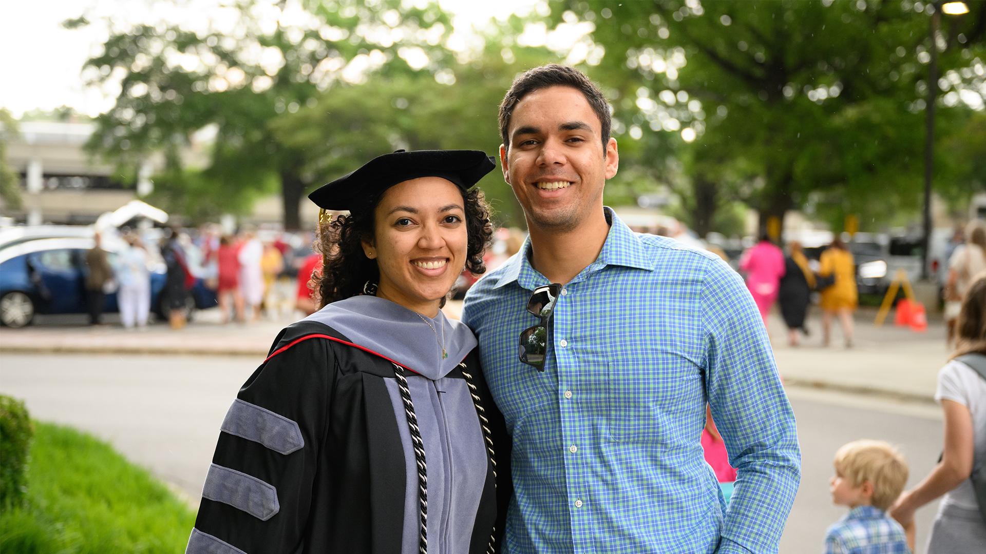 A recent graduate attends the oath and hooding ceremony with friends and family.