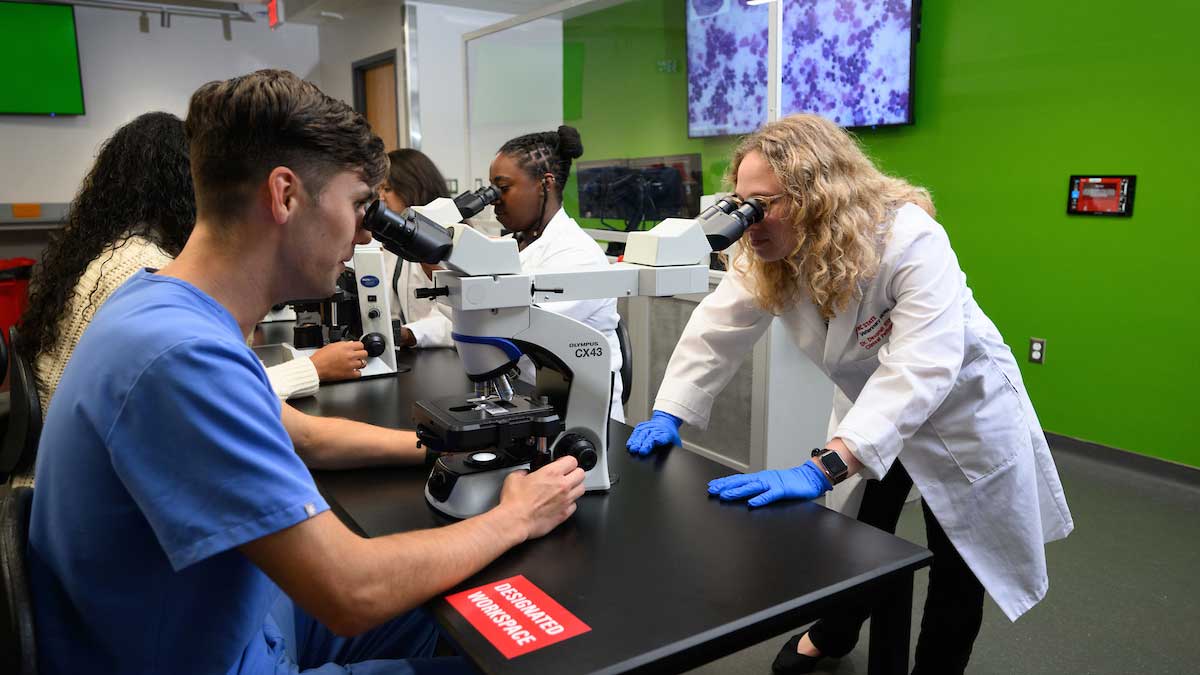 teacher and student looking into microscopes