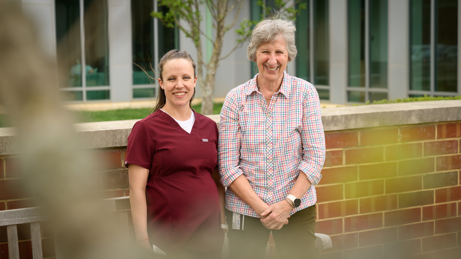 Registered veterinary technician Becky Owens and veterinarian Dr. Kady Gjessing stand in a courtyard at the NC State College of Veterinary Medicine.