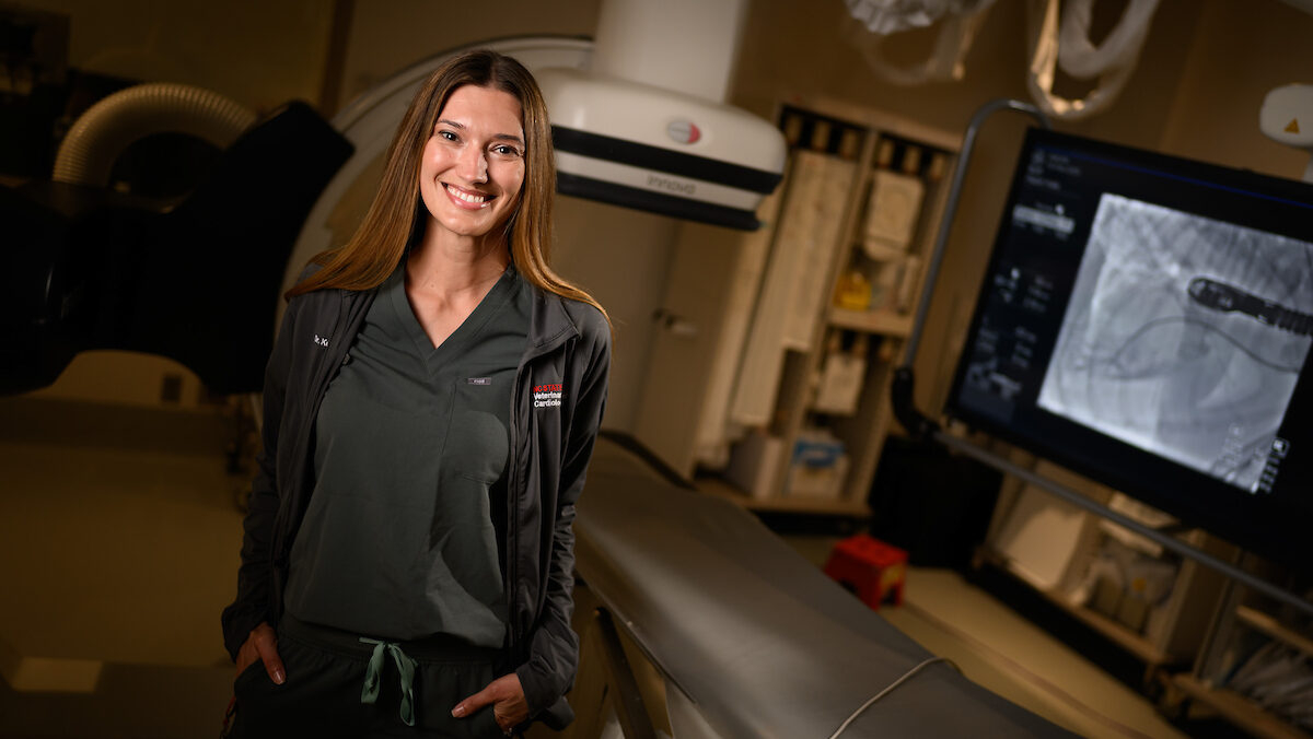 Dr. Kursten Pierce smiles at the camera while confidently standing in the cardiac cath lab at NC State's Veterinary Hospital.