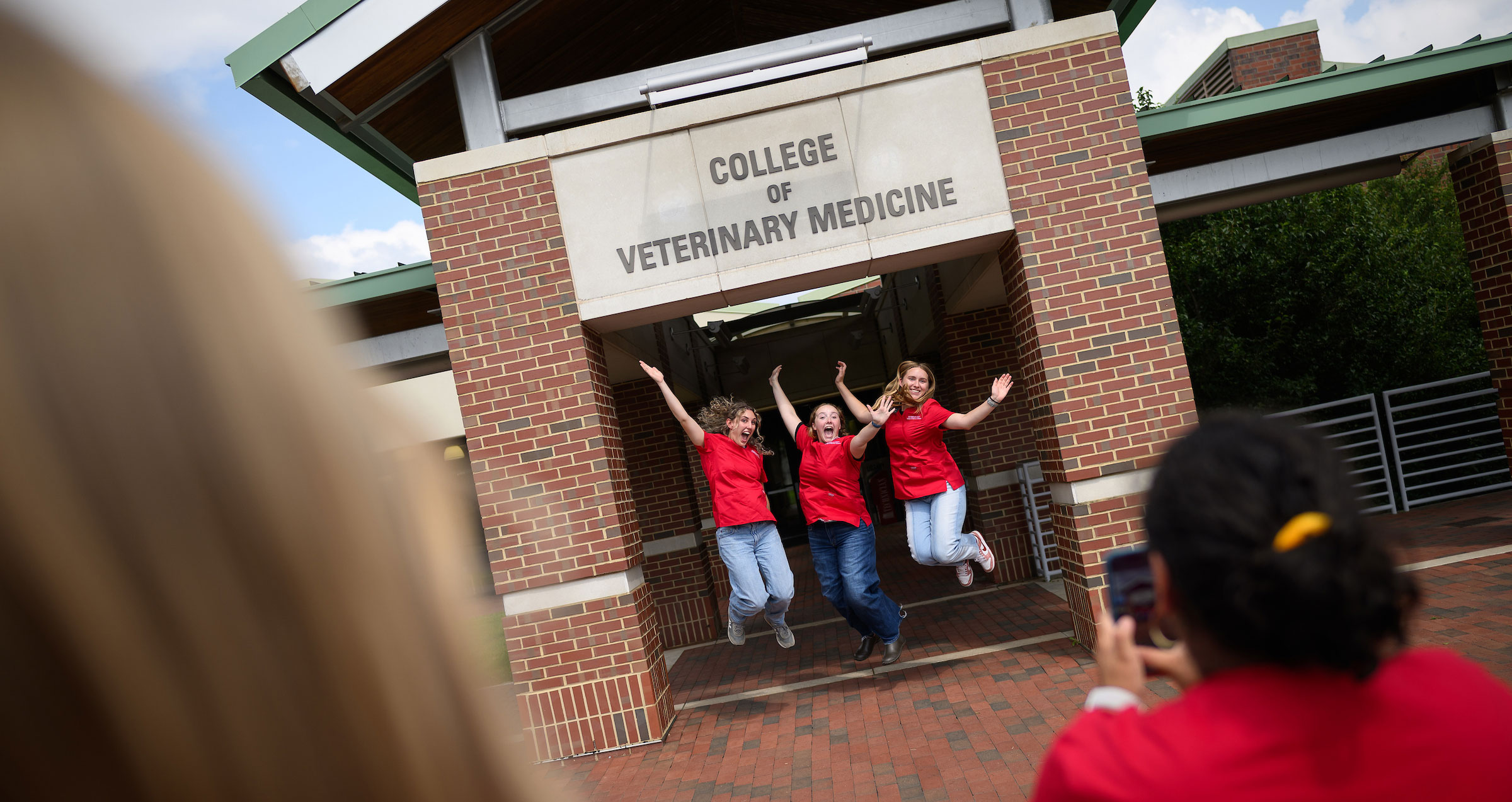 The NC State College of Veterinary Medicine Class of 2029 stands outside the college.